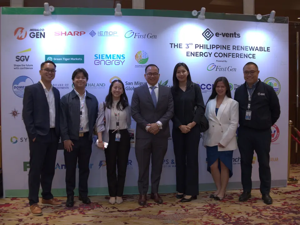 Conference speakers and organizers posing in front of the event backdrop