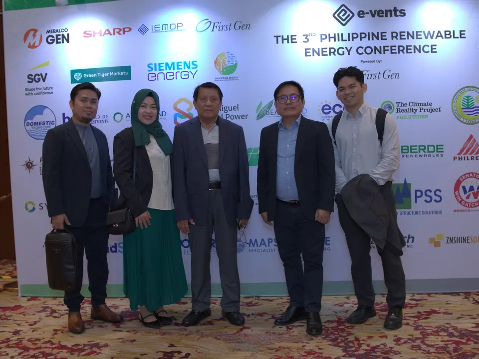 Five delegates posing in front of the renewable energy conference backdrop