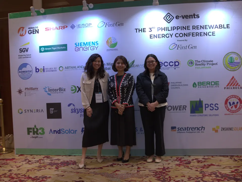 Four women posing in front of the renewable energy conference backdrop