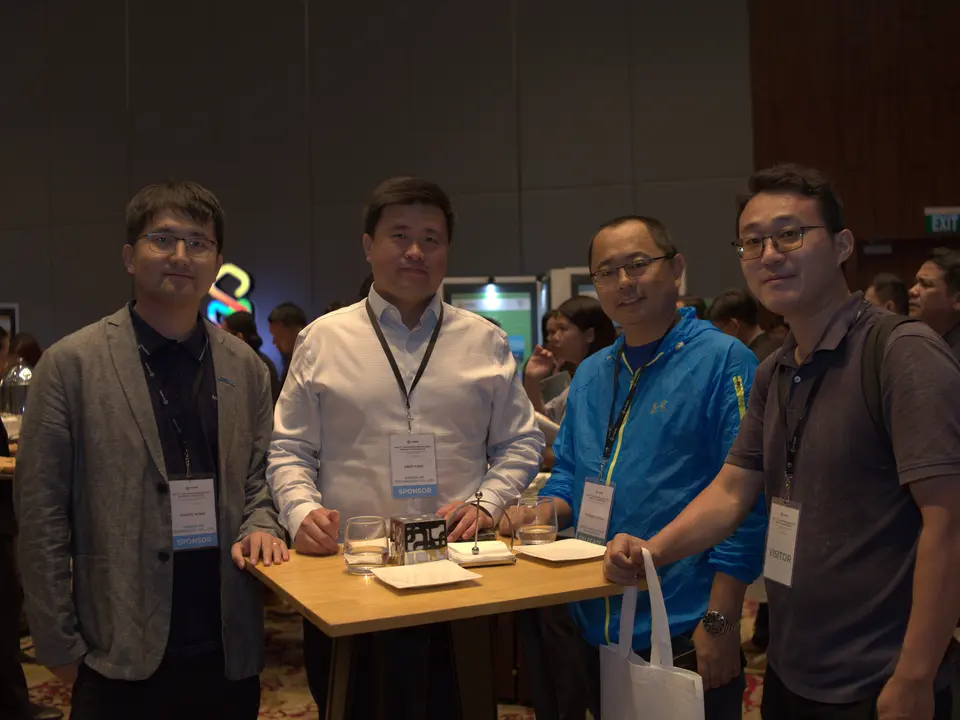 Four exhibitors posing together beside their conference display