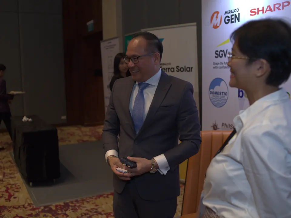 Two renewable energy professionals talking beside the sponsor backdrop