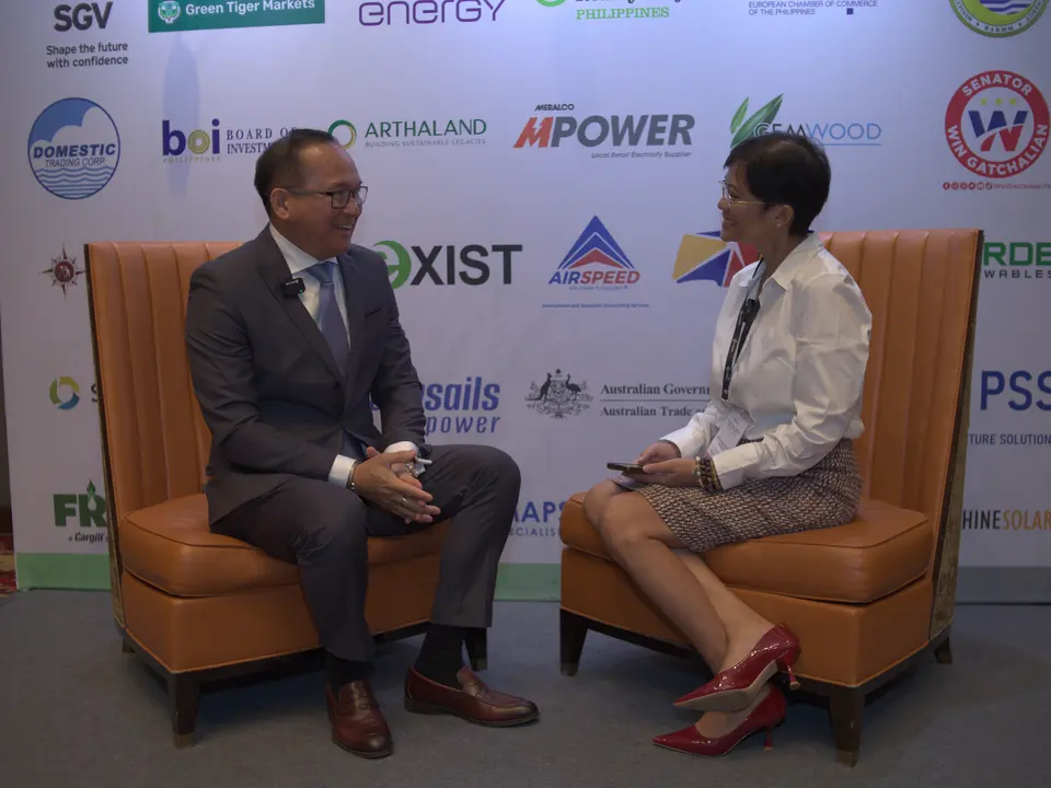 Man and woman recording an interview in front of the sponsor backdrop